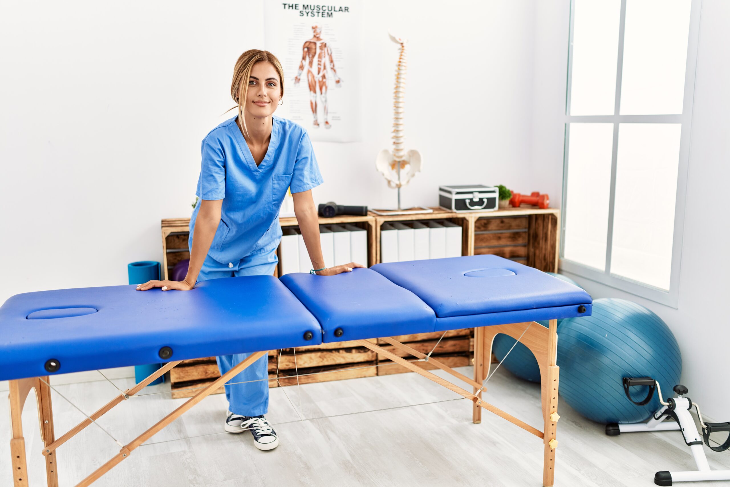 Young caucasian physio therapist smiling happy leaning on table